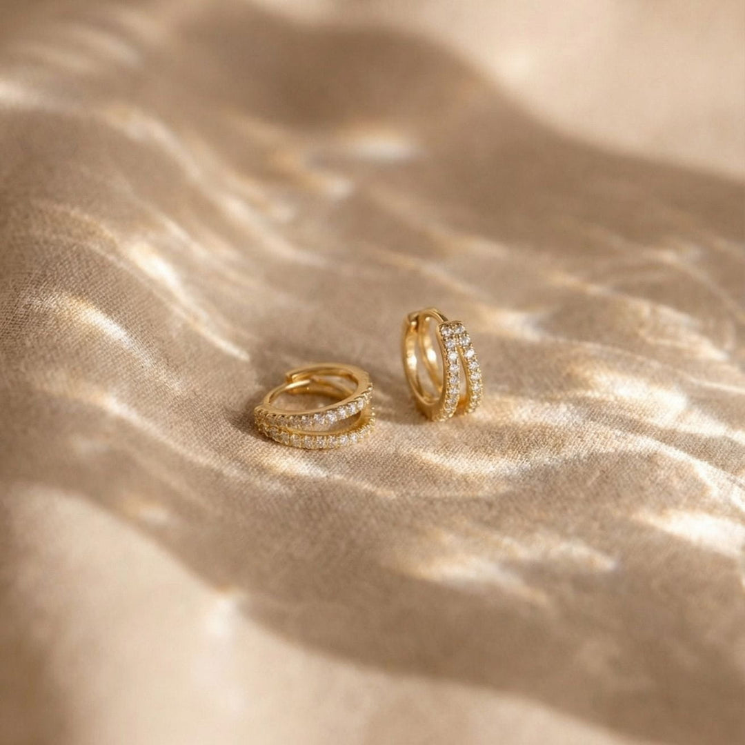 Kaylee Gold Double Pave Huggie Earrings on a soft fabric