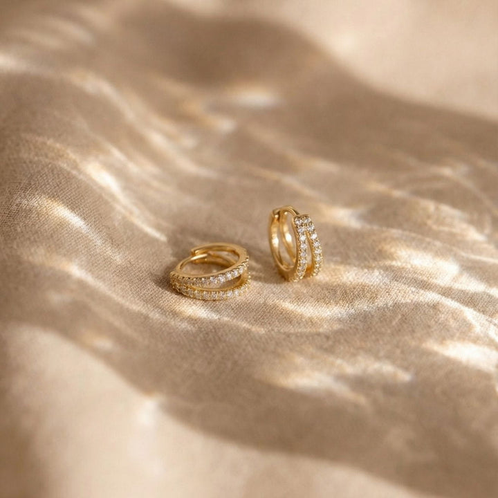 Kaylee Gold Double Pave Huggie Earrings on a soft fabric