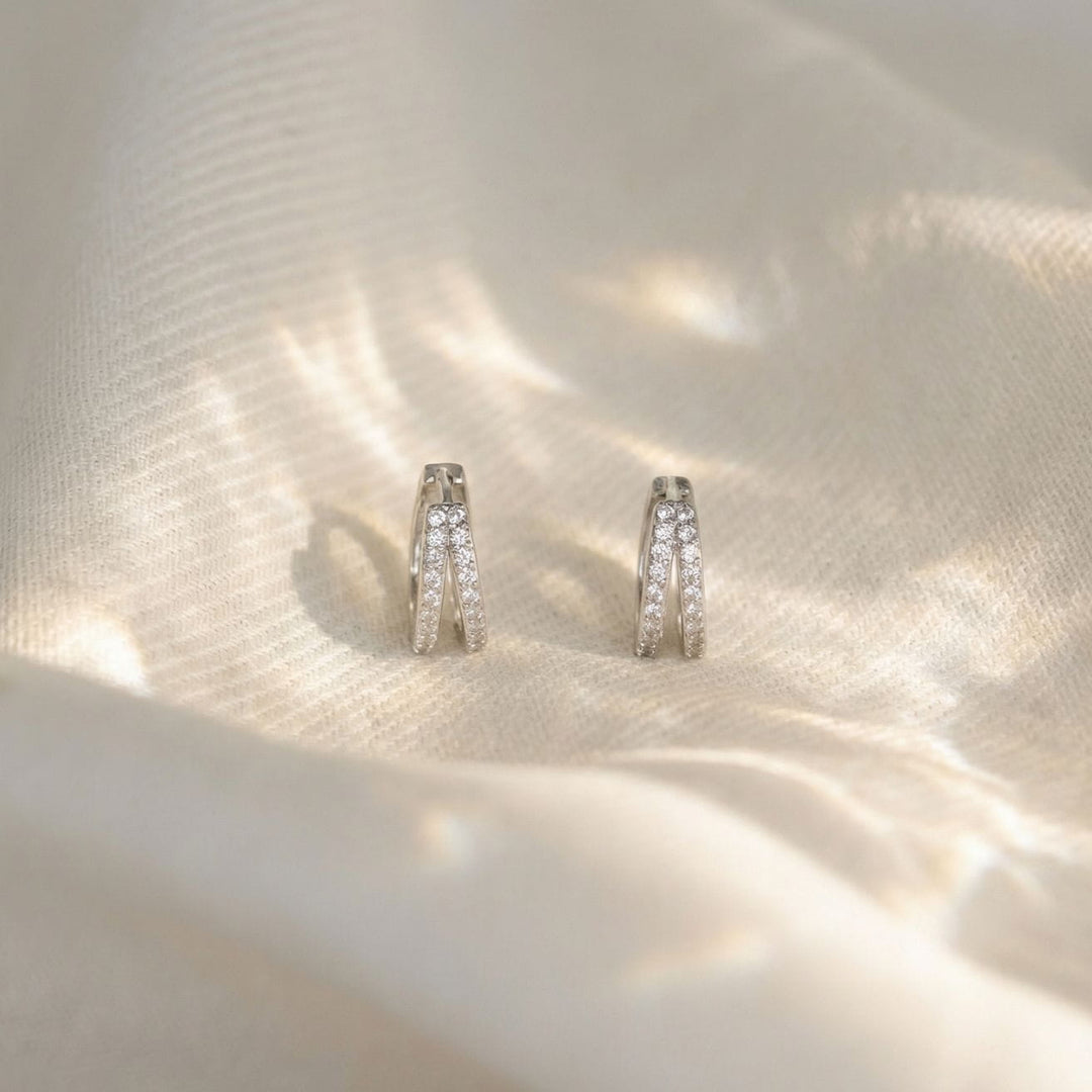 Kaylee Silver Double Pave Huggie Earrings on a soft fabric