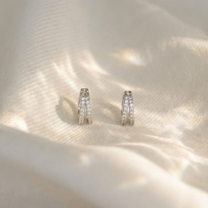 Kaylee Silver Double Pave Huggie Earrings on a soft fabric