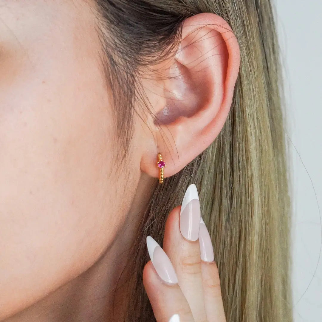 Huggie Hoop Earrings Gold with rose pink CZ stud on model
